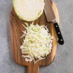 shredded cabbage on a cutting board and a knife