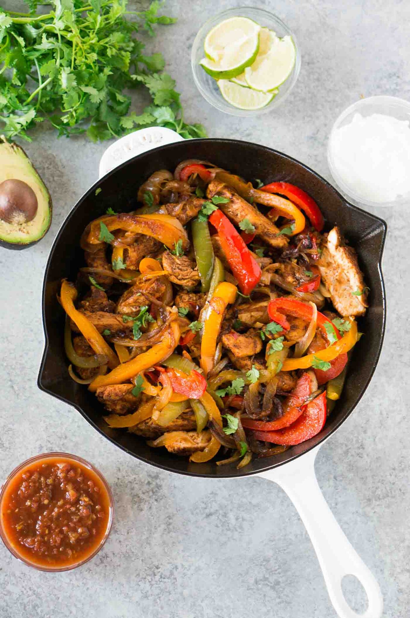 chicken fajitas in a skillet with toppings on a board