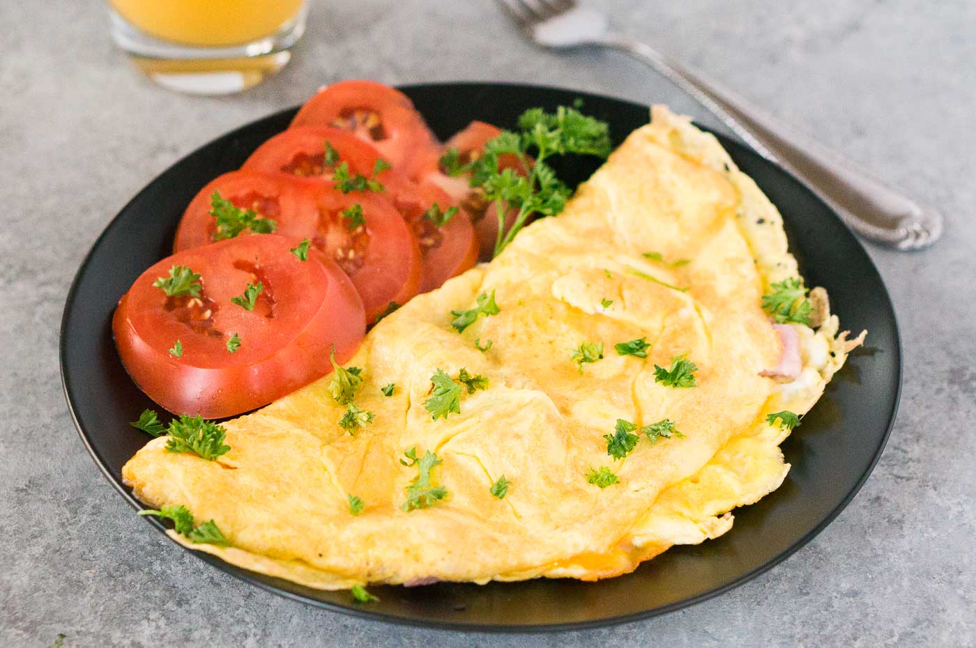 American style omelet on a plate with tomato slices