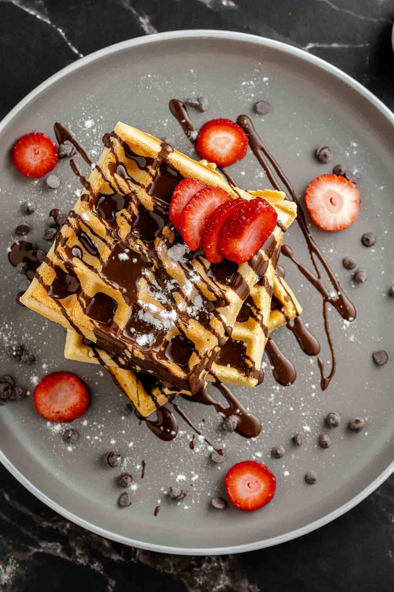 close up image of square waffles on a plate with berries and chocolate