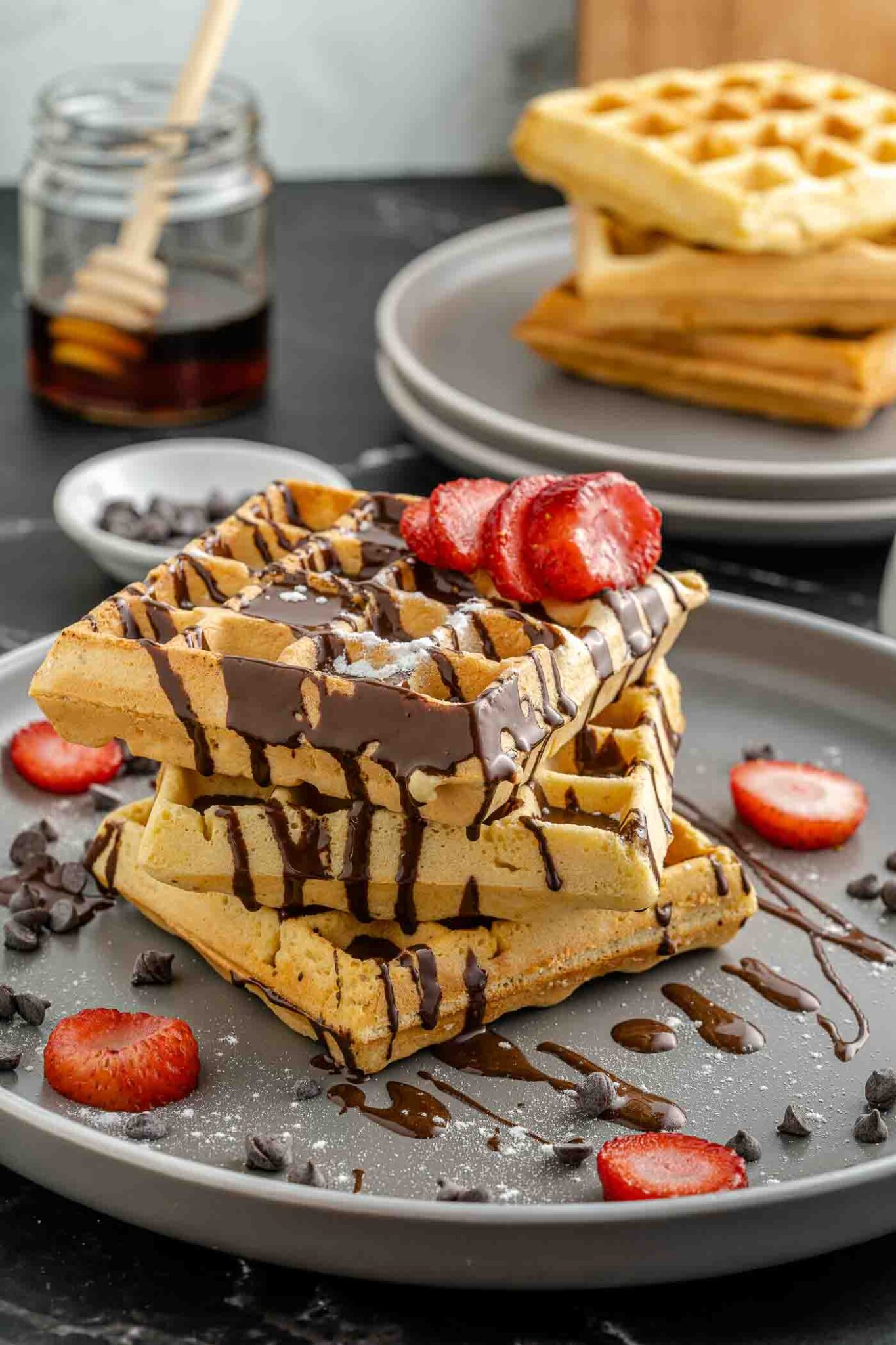 three waffles on a gray plate with chocolate drizzle and strawberry