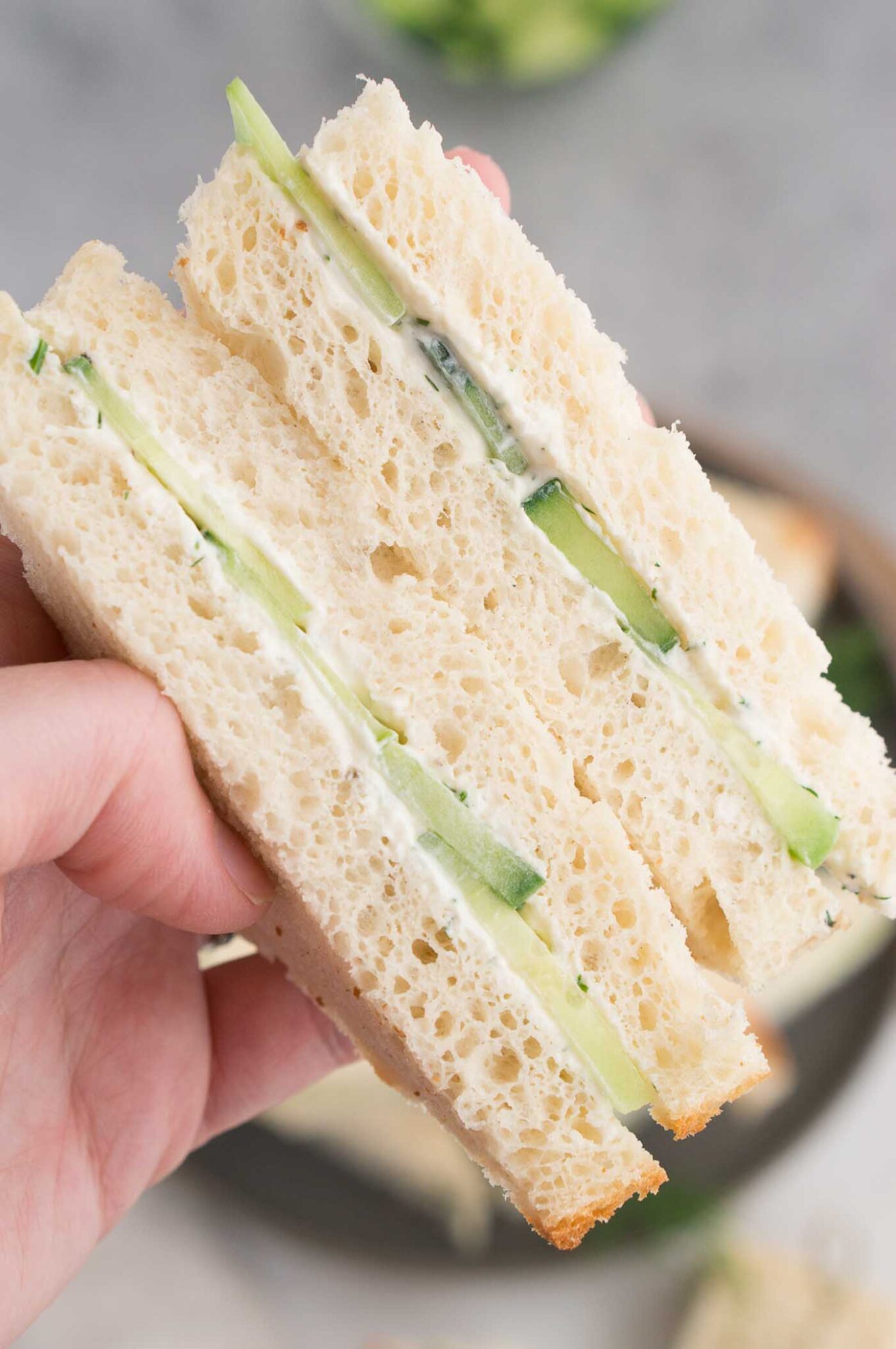 close up image of sandwich made cream cheese and cucumbers