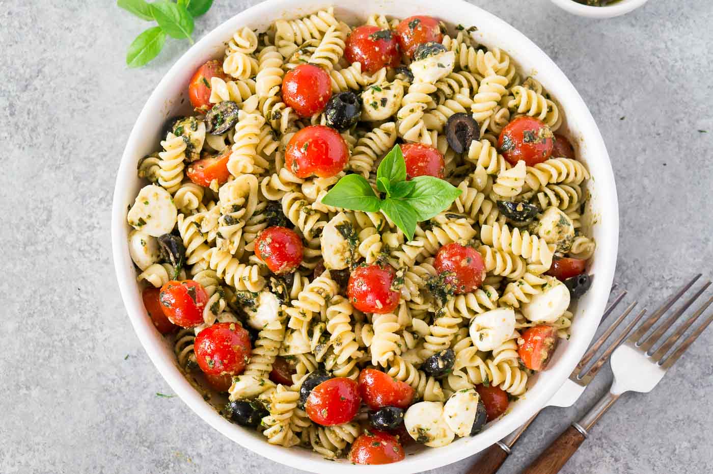 close up images of pasta salad with pesto in a white bowl