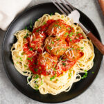 italian meatballs with marinara sauce over spaghetti on a plate