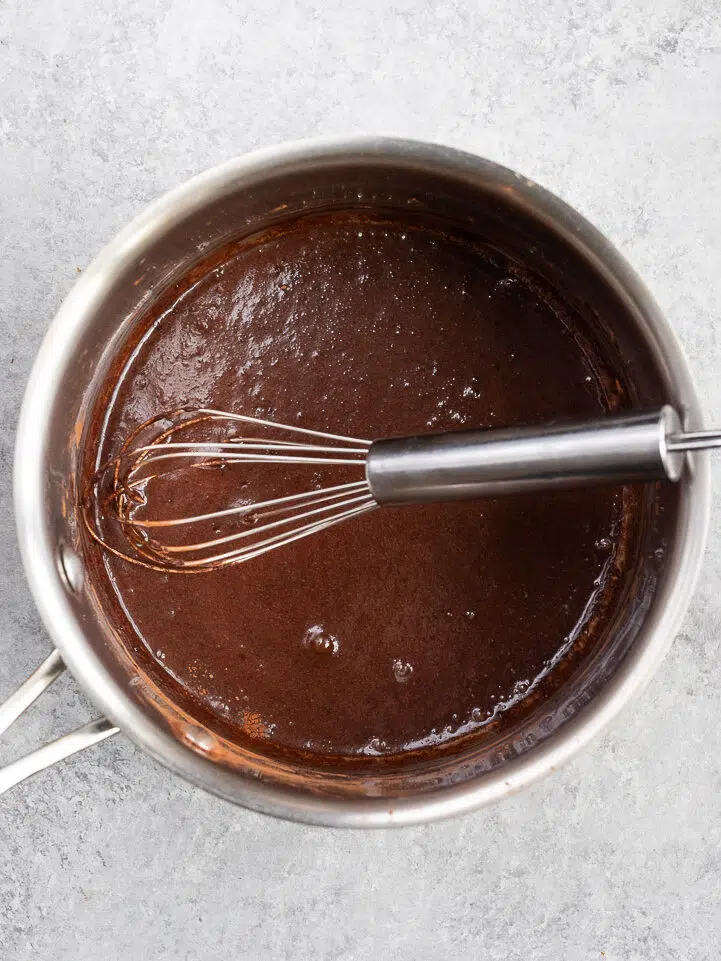 Whisking cocoa powder, honey, and milk to create a smooth slurry in a saucepan