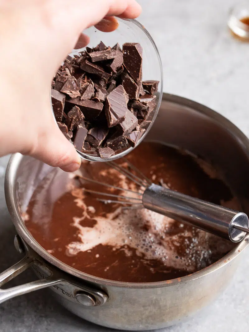 Adding chopped chocolate pieces to the milk and cocoa mixture