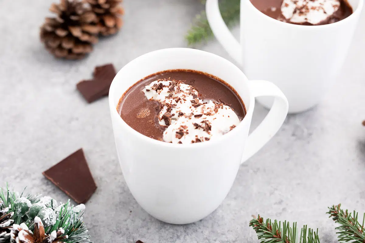 Hot chocolate served in elegant mugs with whipped topping and chocolate shavings