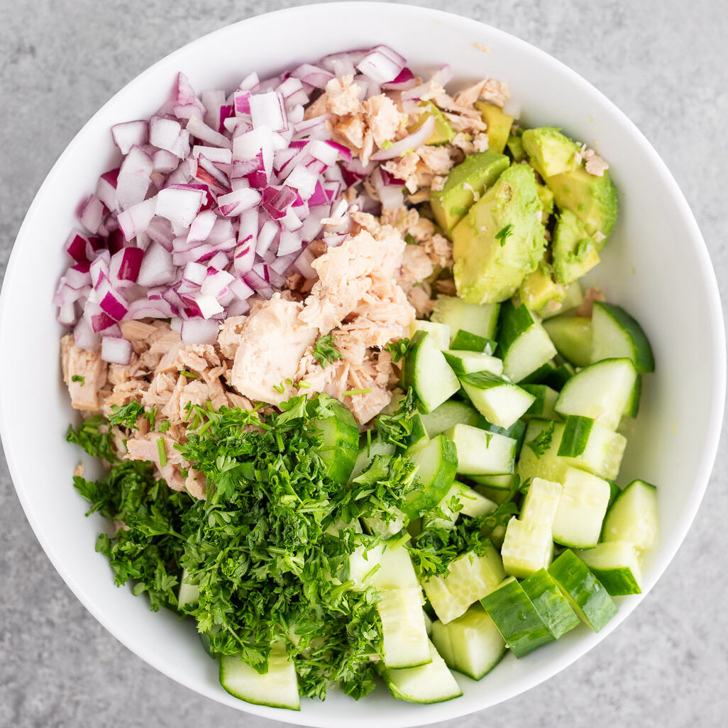 avocado cucumber tuna and red onion in a bowl