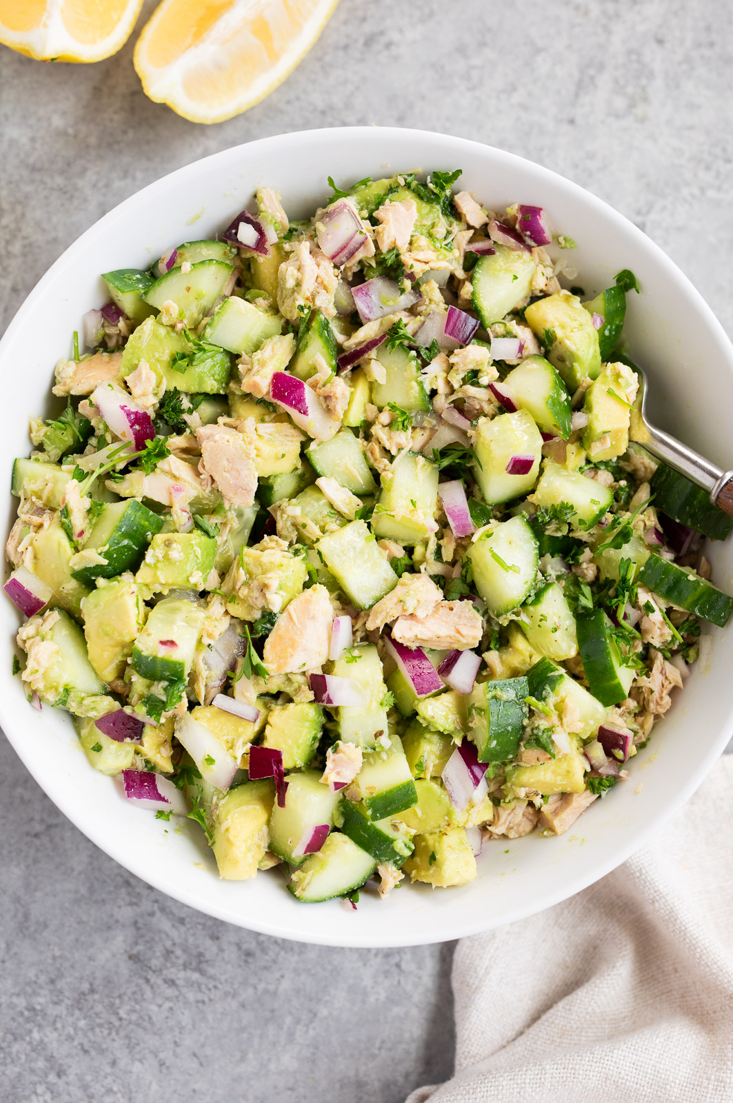 avocadoes cucumber tuna salad tossed with lemon olive oil dressing in a bowl