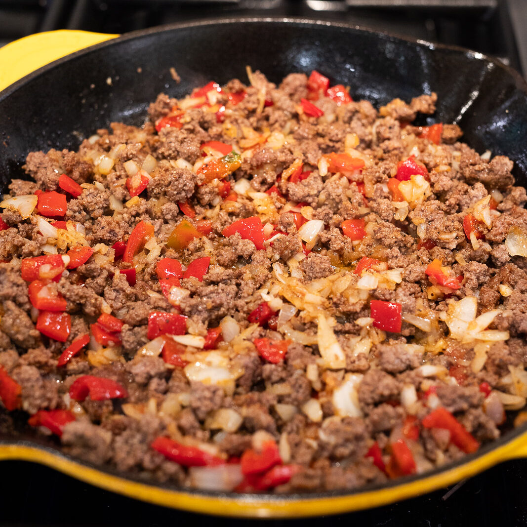 cooking vegetables and ground beef in a skillet
