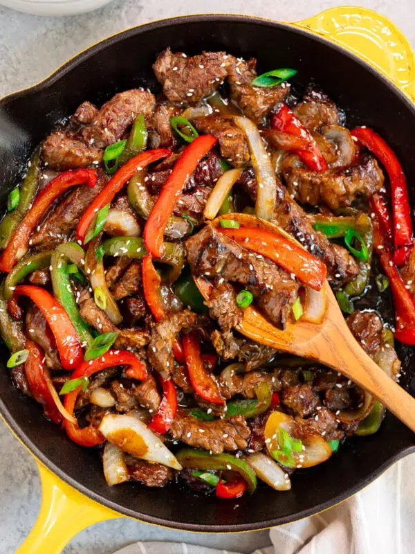 pepper steak in a skillet with a wooden spoon