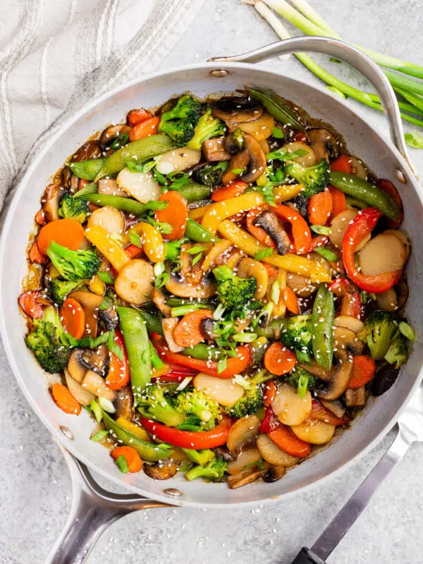 Healthy vegetable stir fry cooked in a skillet with broccoli, bell peppers, mushrooms, carrots, snap peas, and a glossy homemade stir fry sauce