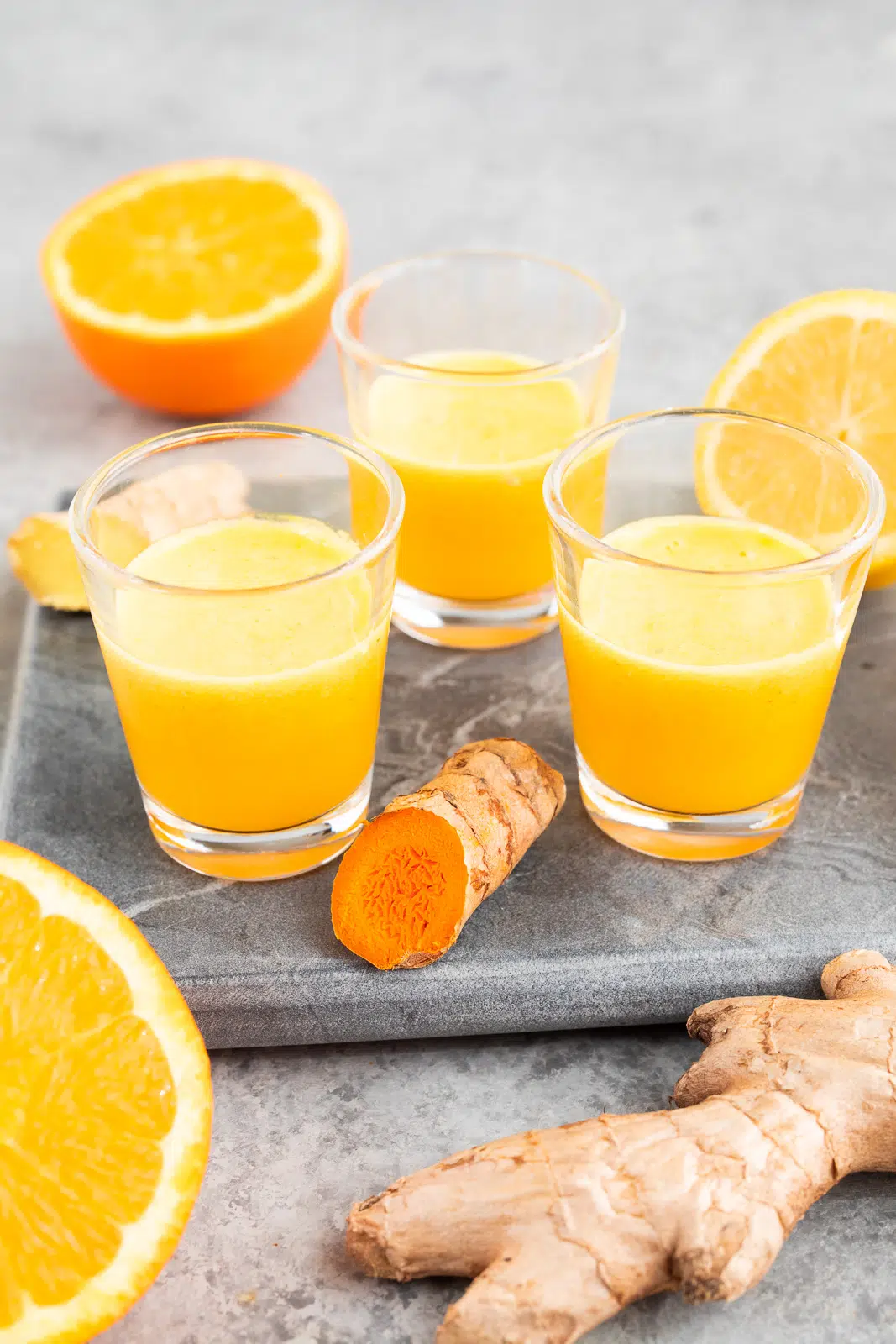 Fresh ginger turmeric shots served in small glasses with citrus
