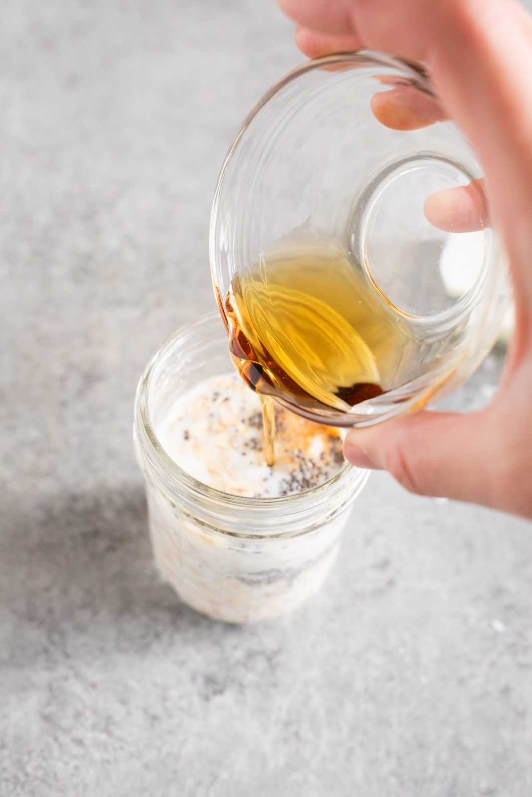 adding oats milk and honey to a glass jar