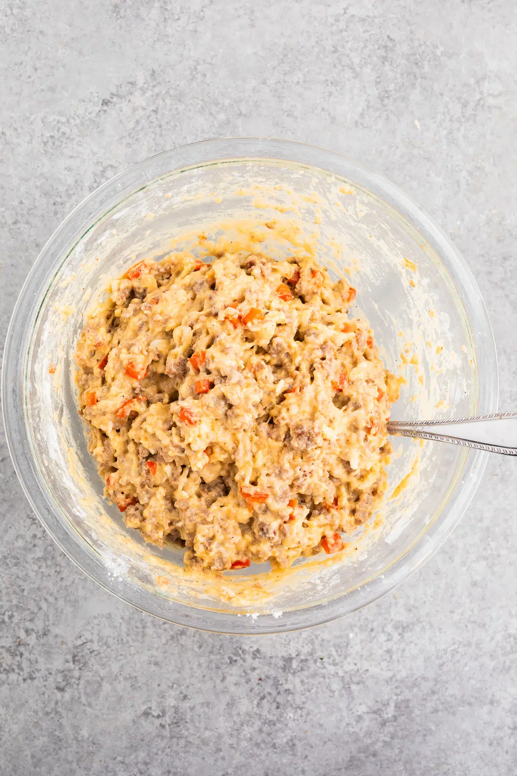 Thick biscuit dough mixed with savory sausage, eggs, cheese, and peppers, ready for baking into make-ahead breakfast biscuits