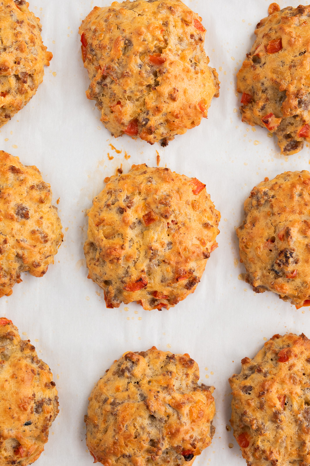 breakfast biscuits with sausage and eggs on a parchment-lined baking sheet