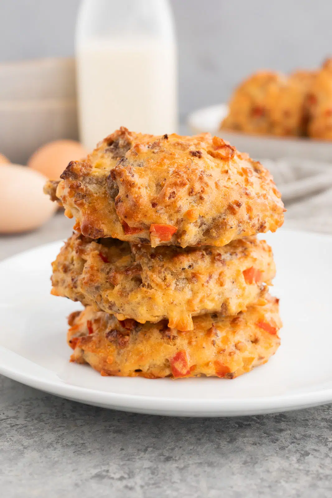 Stacked sausage egg breakfast biscuits with melted cheddar cheese on a plate, ready to serve