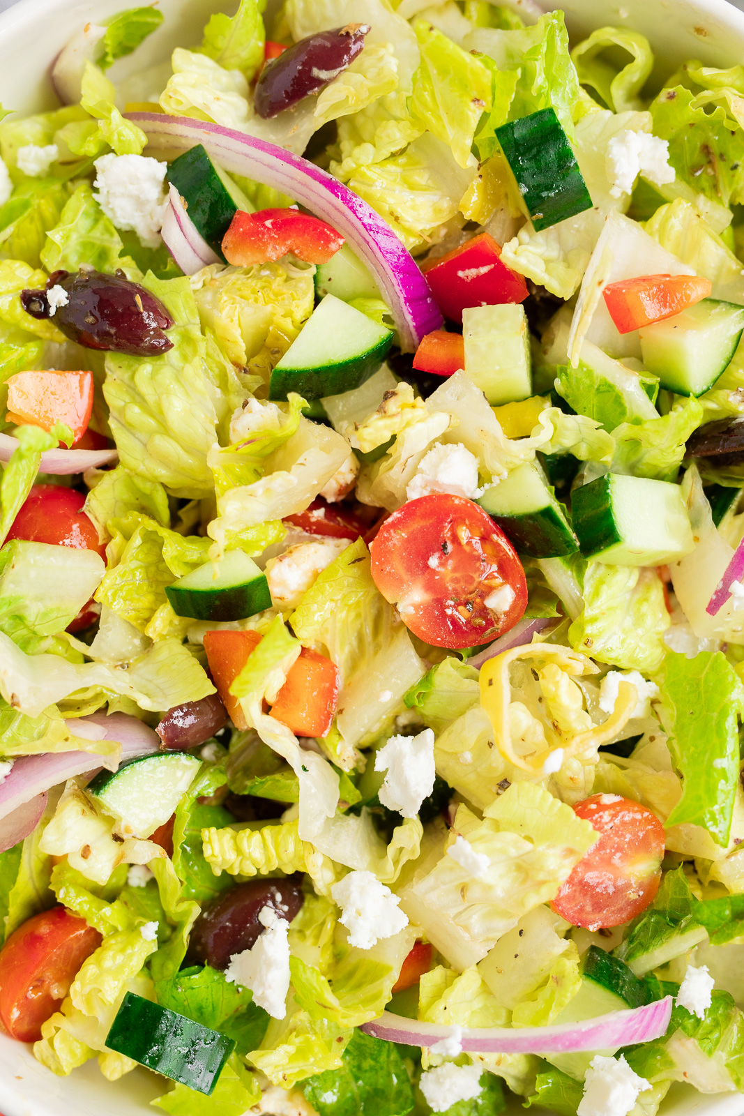 Close-up of Italian chopped salad with crisp romaine, cucumbers, cherry tomatoes, red pepper, olives, red onion, feta, and pepperoncini