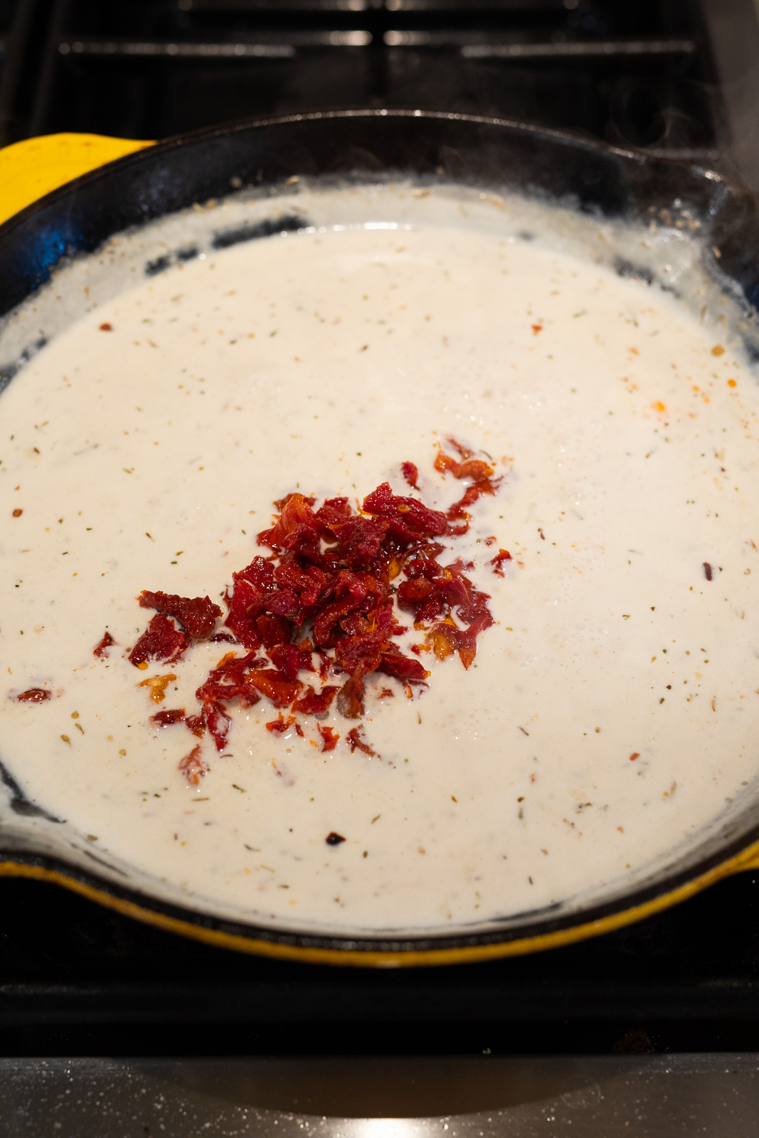 mixing in sun dried tomatoes with the creamy sauce