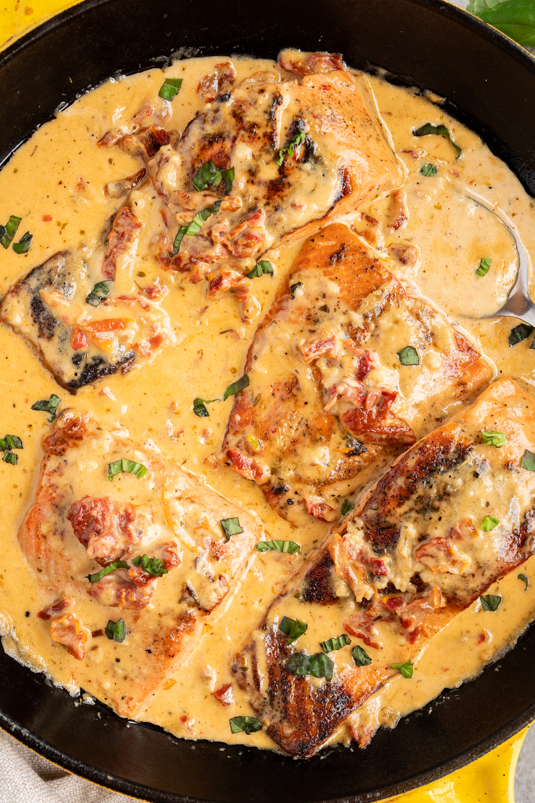 close up image of salmon cooking in a creamy sun-dried tomatoes sauce