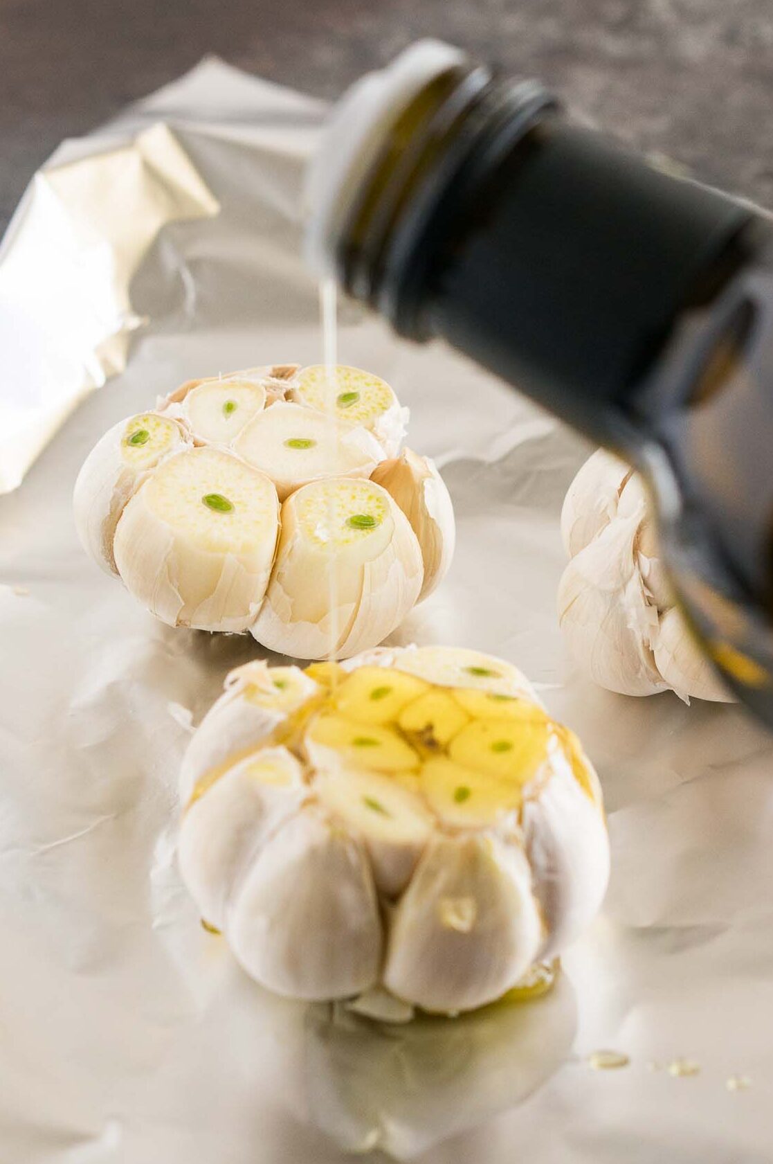 drizzling olive oil over garlic bulbs
