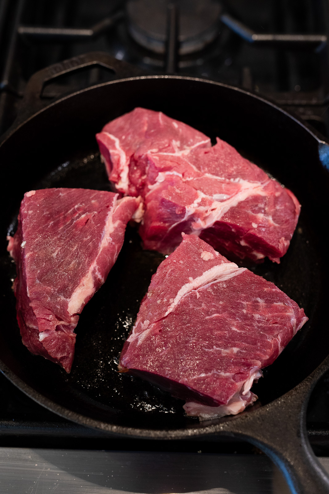 browning pieces of chuck roast in a cast iron skillet