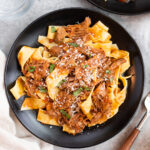 tender beef ragu served with pappardelle pasta on a black plate