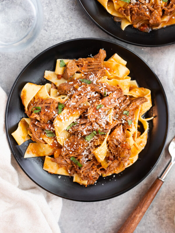tender beef ragu served with pappardelle pasta on a black plate