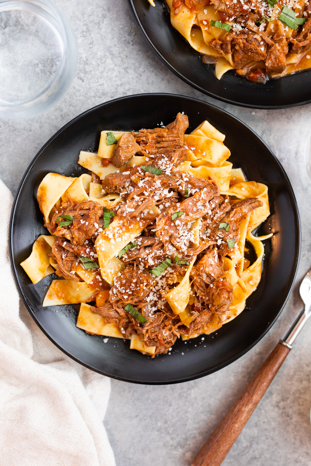 tender beef ragu served with pappardelle pasta on a black plate