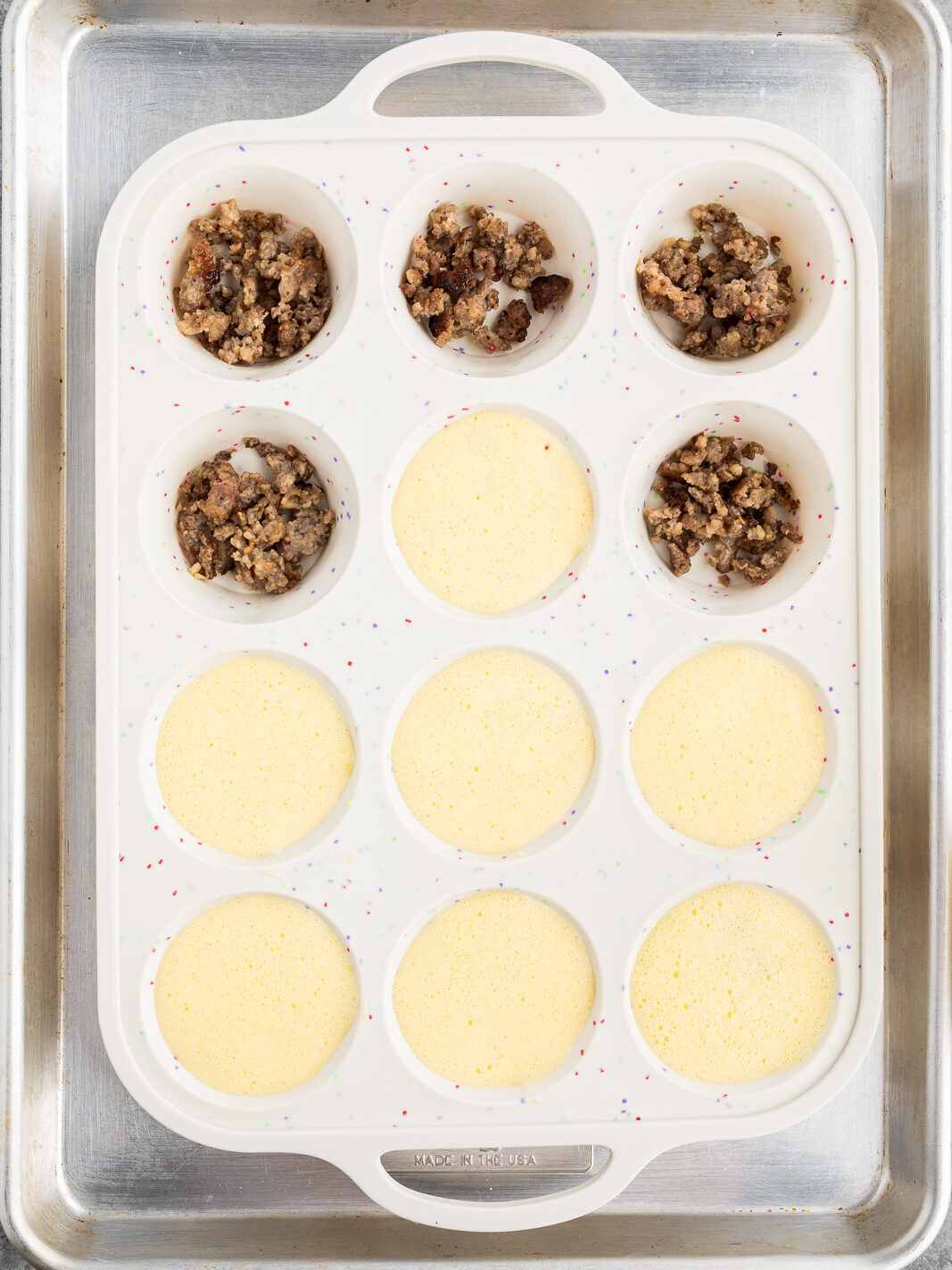 filling muffin cups with browned sausage and egg cottage cheese mixture