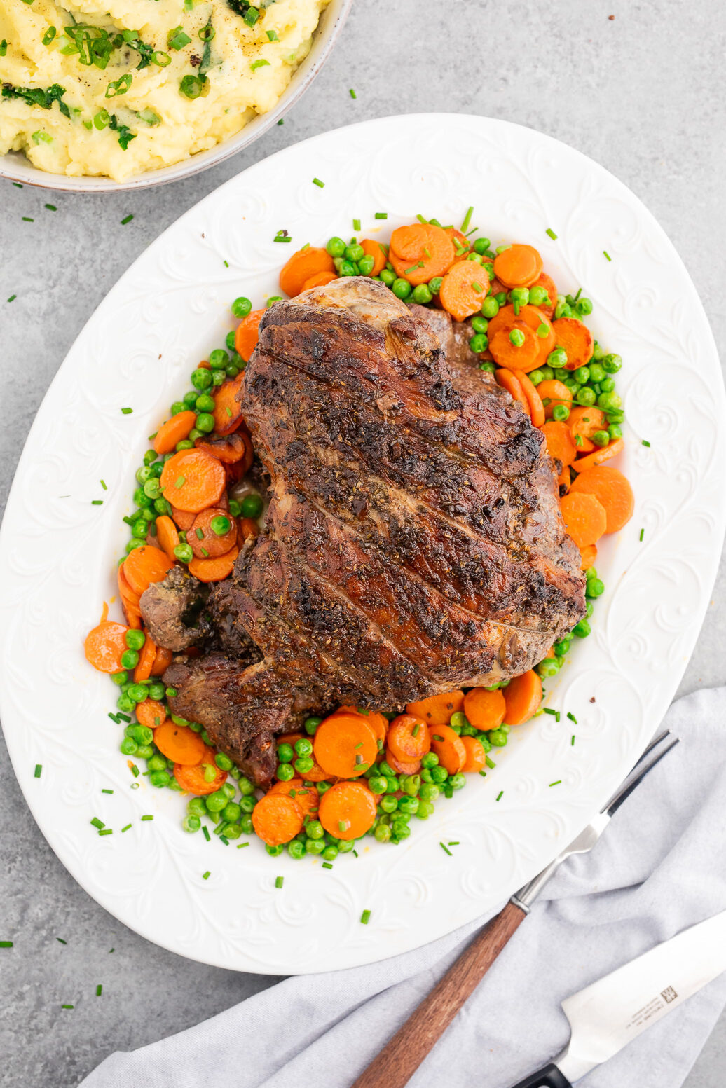 Herb roasted leg of lamb served with carrots, peas, and mashed potatoes