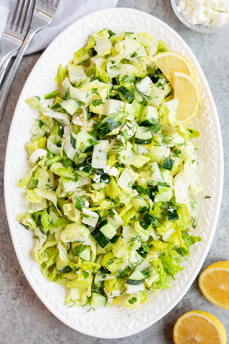Traditional maroulosalata Greek lettuce salad served on a platter with fresh herbs and feta