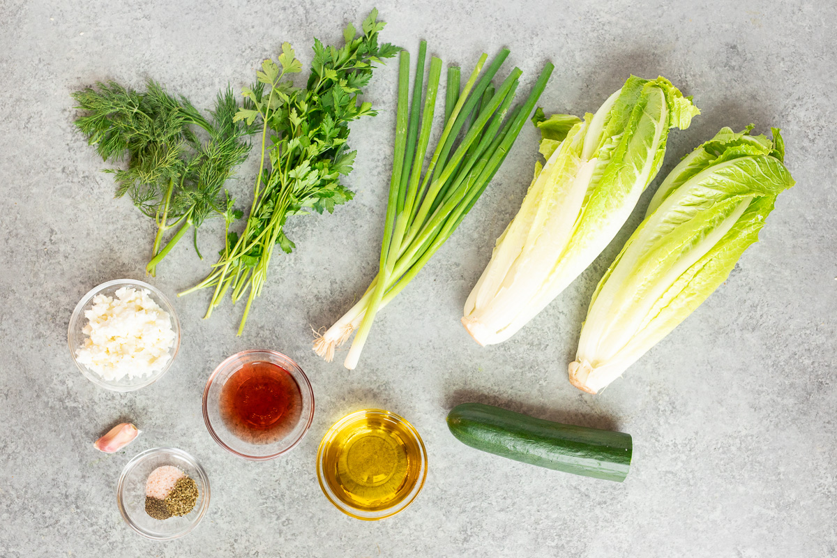 ingredients for Maroulosalata including crisp lettuce, cucumber, fresh parsley, green onion, dill, and vinaigrette
