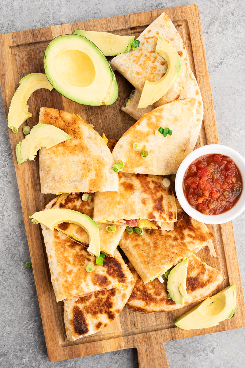savory breakfast quesadillas made with eggs, bacon and cheese on a cutting board