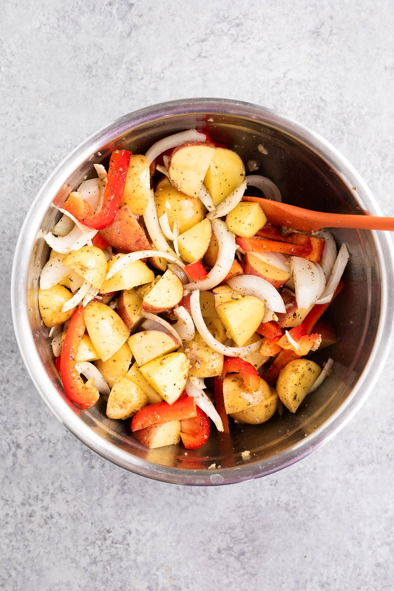 mixing sausage and vegetables with aromatics in a bowl