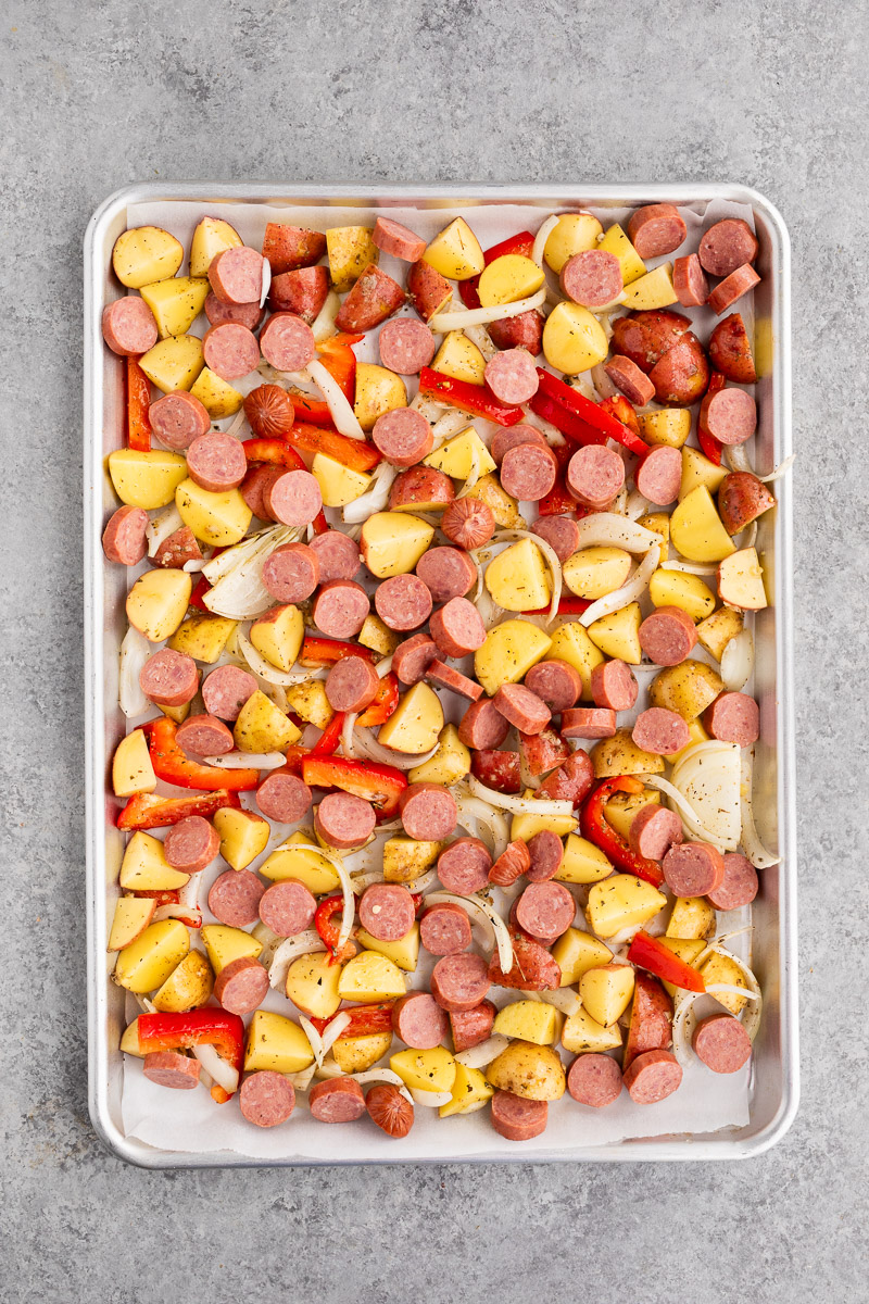 sausage and potatoes and onions and peppers on a baking sheet