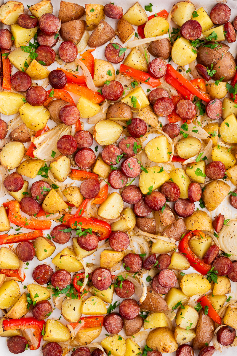 sausage potatoes onions and peppers baked in the oven on a baking sheet